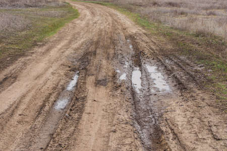 Country road. Autumn dirt road. Puddle and mud with deep ruts.の写真素材