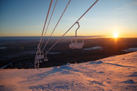 Snowboarder ride on the top of snowy hill in ski resort during calm winter sunset. Scenery of athlete - wallpaper with space for your montageの写真素材