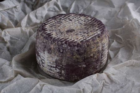 Close up of soft French cheese with purple crust on paperの写真素材