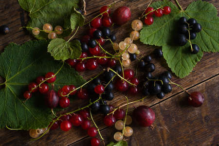 Flat lay. Red currant, blackcurrant, white currant with leafs on the old wooden tableの写真素材