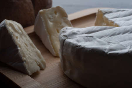 Close up of Fresh French Brie cheese and a one slice on a bamboo plate with breadの写真素材