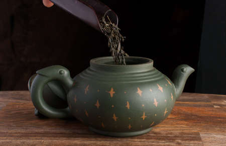 Green traditional chinese Yixin clay teapot with cicada on the cover. On the wooden table and black backgroundの写真素材