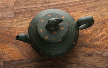Green traditional chinese Yixin clay teapot with cicada on the cover. On the wooden table and black backroundの写真素材