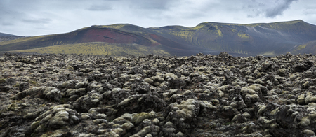 Frozen lava against mountains and gloomy leaden sky