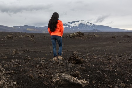 girl in an orange jacket stands on a stoneの写真素材