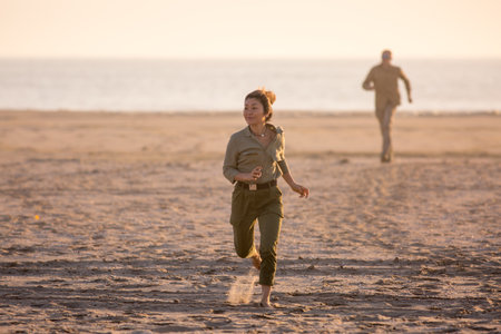 A man runs after a woman on an ocean beach in Namibia, Africaの写真素材