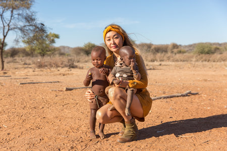 Namibia, Africa June 18, 2019: Beautiful European girl squatting and holding two small black...