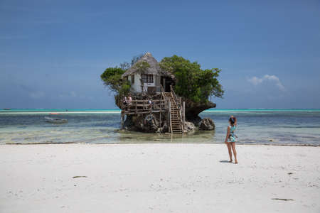 Zanzibar, Tanzania, January 23, 2021: A girl in beachwear walks to a restaurant located on a cliff in the azure sea not far from the coast.のeditorial素材