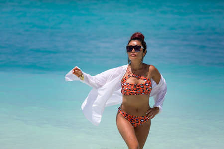 Young beautiful girl of Asian appearance in a white wet shirt comes out of the turquoise oceanの写真素材