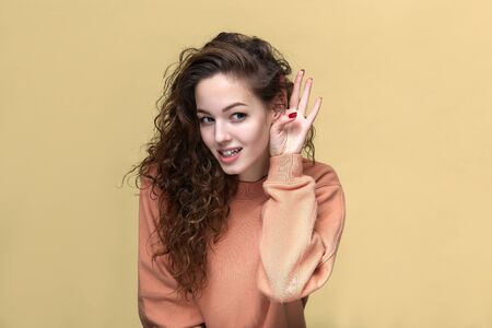 Portrait of a young beautiful woman wearing sweatshirt posing isolated over yellow background
