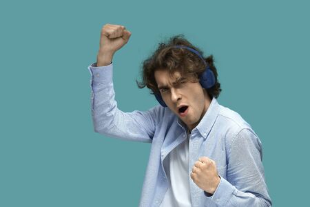 Portrait of a young beautiful man wearing white t-shirt and blue shirt in blue headphones. dancing...