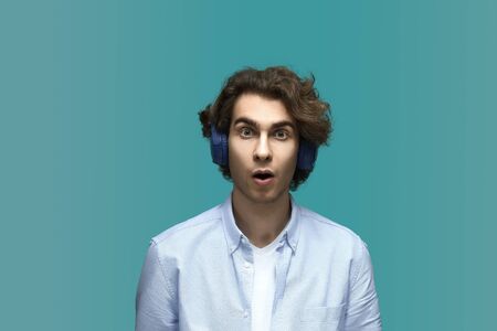 Wondered of sounds. Portrait of a young beautiful man wearing white t-shirt and blue shirt in...