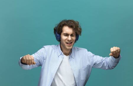 swanky sound. Portrait of a young beautiful man wearing white t-shirt and blue shirt in blue...