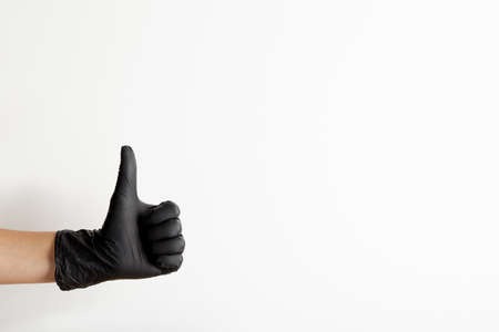 Female hand in black latex gloves shows thumb up gesture, isolated on white background with free space for textの写真素材