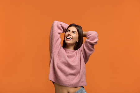 Im not afraid of problems. Portrait of laughing young female keeps hands behind head, enjoys leisure...