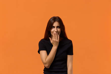 This is a dirty joke. Positive caucasian woman in black t-shirt covering mouth and feels shy hears...