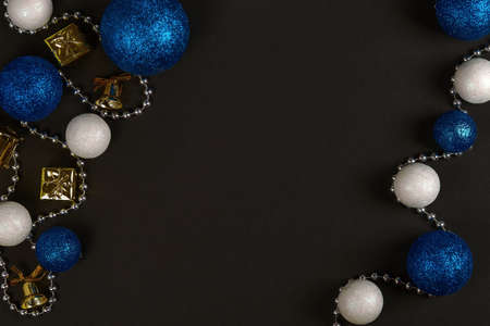 Horizontal shot of three blue balls and three decorative snowballs and beads at left and right on black background. Top view with copy space for textの写真素材
