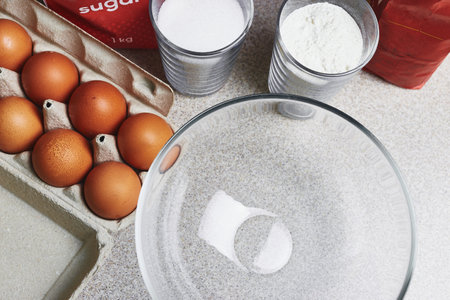 Culinary class in a kitchen. Ingredients for baking cake on a table. Cooking set. Dozen of tinted brown chicken eggs, flour, pack of sugar and a transparent bowl. Close-up viewの写真素材