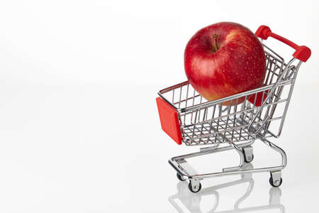 fresh red apple on chopping cart isolated over white background. Electronic commerce, online shopping, fast delivery. add fruits to basket.の写真素材