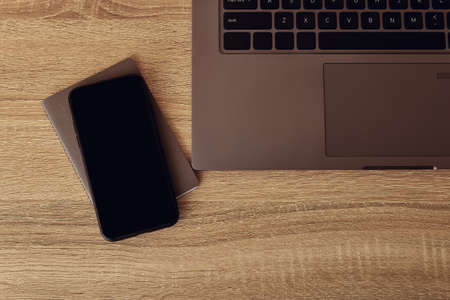 Workspace desk. Top view to notepad with mobile phone and laptop keyboardの写真素材