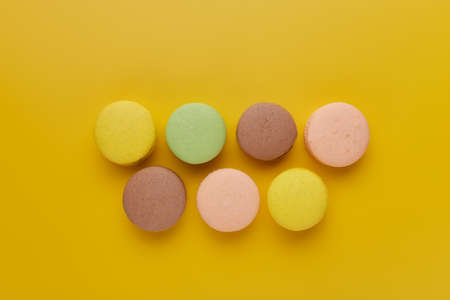 Macaroon. Colorful cake macaron with pastel tones are staggered on an yellow background. Top view of almond cookiesの写真素材