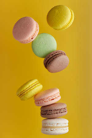 Macaroon. Colorful cake macaron with pastel tones fall at the stack macaroon on an yellow background. Top view of almond cookiesの写真素材