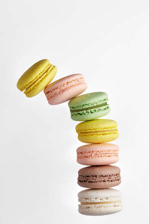 Vertical photo of macaroon. Colorful stack of cake macaron with pastel tones fall a side on white background. Top view of almond cookiesの写真素材