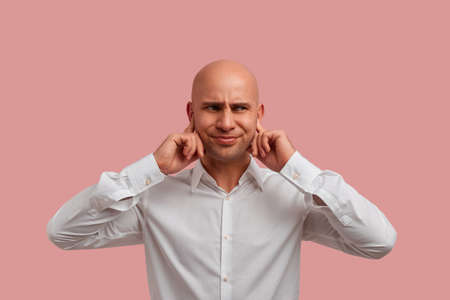 Can you play another sound. Irritated bald guy with bristle in white shirt plugs ears, dissatisfied...