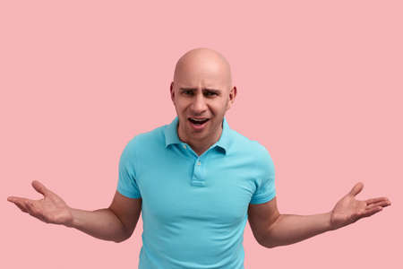How come. Displeased bald homosexual man with bristle is disappointed with result, upset with work or product, throws hands.の写真素材