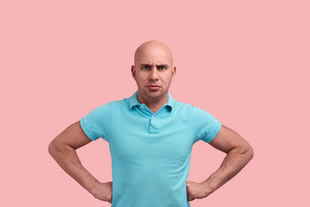 Who offended him. Disgruntled bald homosexual man with bristle, hold hands on the waist, came to showdown, fight for justice.の写真素材