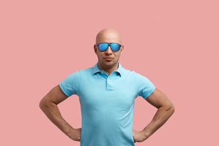 Serious handsome bald unshaven homosexual man keeps hands on waist, stays akimbo, ready to dispute, knows truth.の写真素材