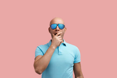 Sleepy handsome bald unshaven homosexual man yawns, wants to sleep, tired after workout, closes mouth with hand.の写真素材