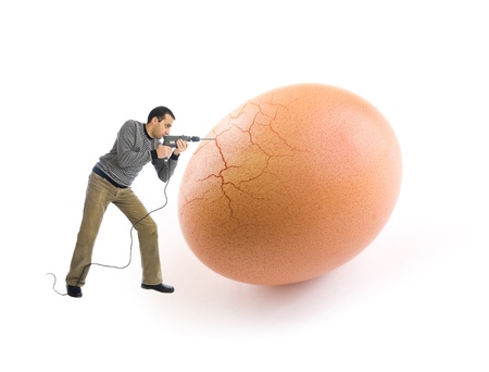 Young man cracking an egg using a drill toolの写真素材