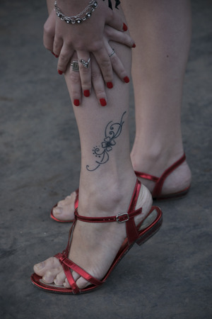 female feet in red sandals with a tattooの写真素材