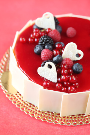 Summer Berries Cake with white chocolate hearts, on a red background の写真素材