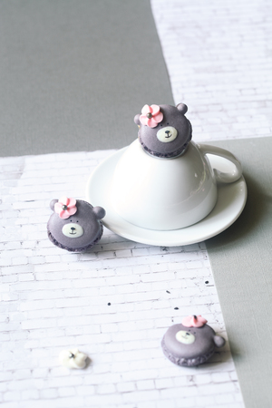 Teddy Bear Macarons with Black Sesame Filling, on white upside down cup, on light gray background.の写真素材