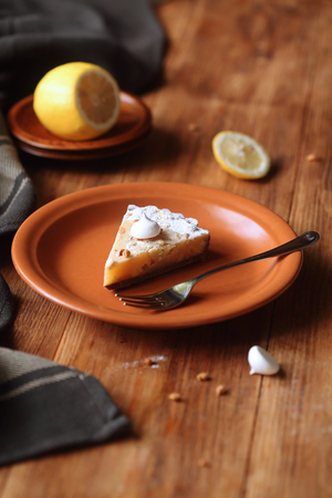 Lemon Tart with chocolate cookies and meringue cookies, on brown plate, on wooden table.の写真素材