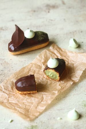 Traditional French Eclairs filled with Matcha Tea Pastry Cream and topped with chocolate glaze,...