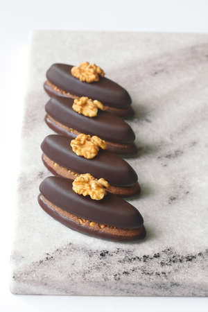 Chocolate Cookie Bar with Praline, garnished with walnut halves and chocolate spirals, on light...