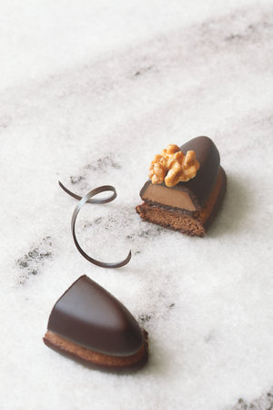 Chocolate Cookie Bar with Praline, garnished with walnut halves and chocolate spirals, on light marble board, on white background.の写真素材