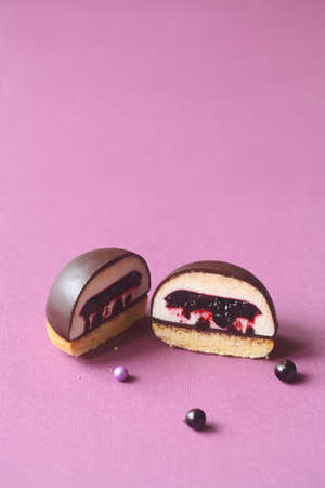 Mini Dome Cakes - Ptichye Moloko (Bird's Milk) - traditional Russian (Soviet) Souffle Cake, with black currant filling, covered with chocolate glaze and decorated with sugar balls, on purple backgrounの写真素材