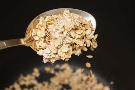 Oatmeal is poured out of the spoon. Cooking porridge close-up.