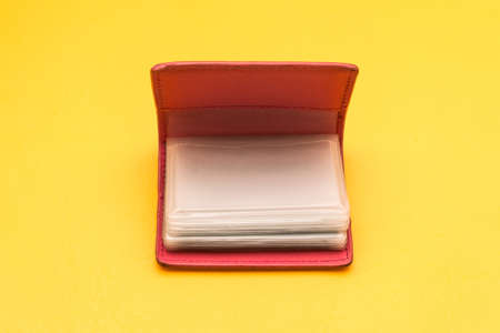 Thick red business card holder on a yellow background. Pink card book