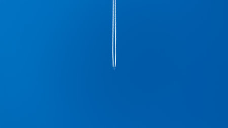 The plane is flying high in the clear blue sky. Condensation footprint. A straight line in the sky.の写真素材