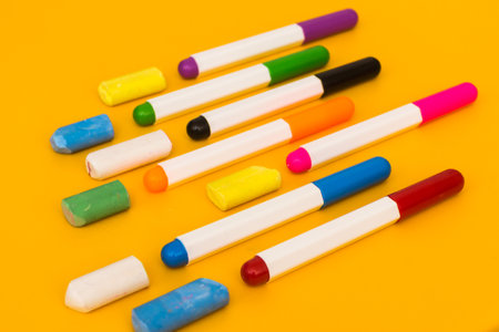 Multi-colored markers and crayons on a yellow background. Photo for drawing.