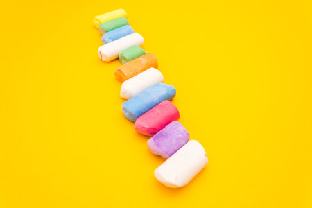 Childrens drawing crayons lie in a row on a yellow background. Multi-colored chalk close-up.の写真素材