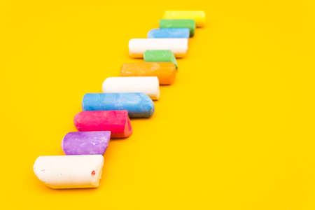 Childrens drawing crayons lie in a row on a yellow background. Multi-colored chalk close-up.の写真素材