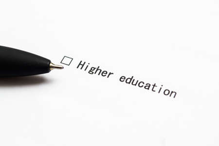 Pen and the inscription Higher education with a check mark on white paper. Questionnaire.の写真素材
