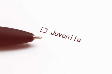Pen and the inscription Juvenile with a check mark on white paper. Questionnaire.の写真素材