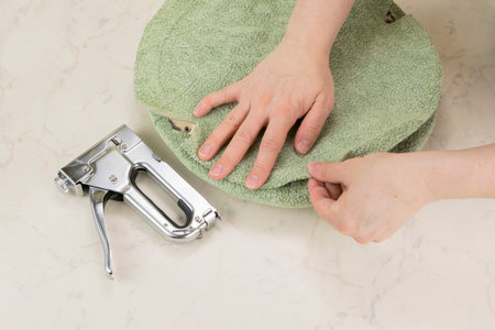 upholstering a padded part of soft chair by staple gun with textile coveringの写真素材